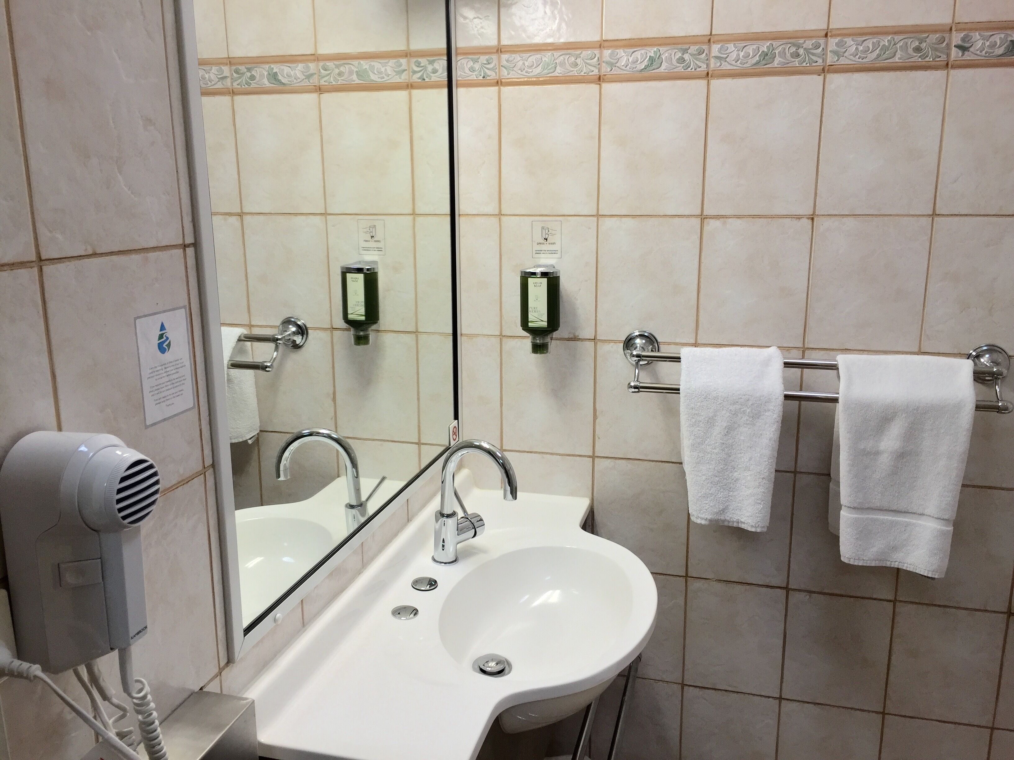 A bathroom with a sink, mirror, towel rack, and hand dryer.