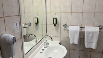 A bathroom with a sink, mirror, towel rack, and hand dryer.