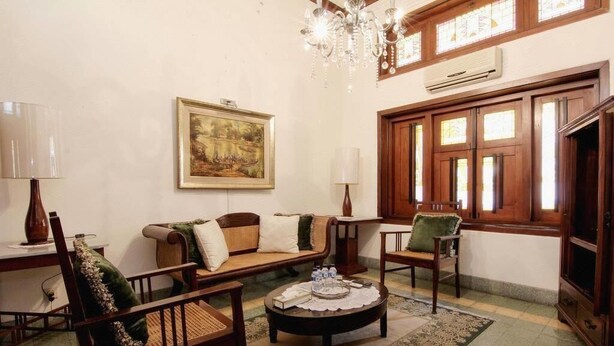 Un salon chaleureux avec un canapé, des fauteuils, une table basse et un lustre.
