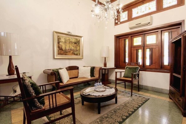 A cozy living room with a sofa, chairs, a coffee table, and a chandelier. - Roemahkoe Heritage Hotel (Surakarta)