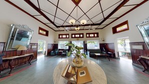 A spacious lobby with a high ceiling, wooden paneling, and large windows. - Roemahkoe Heritage Hotel (Surakarta)