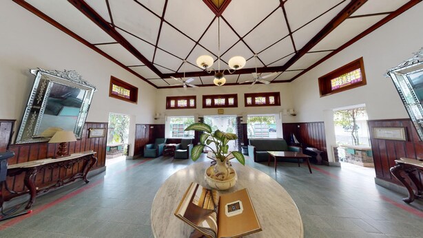 Een ruime lobby met een hoge plafond, houten lambrisering en grote ramen.