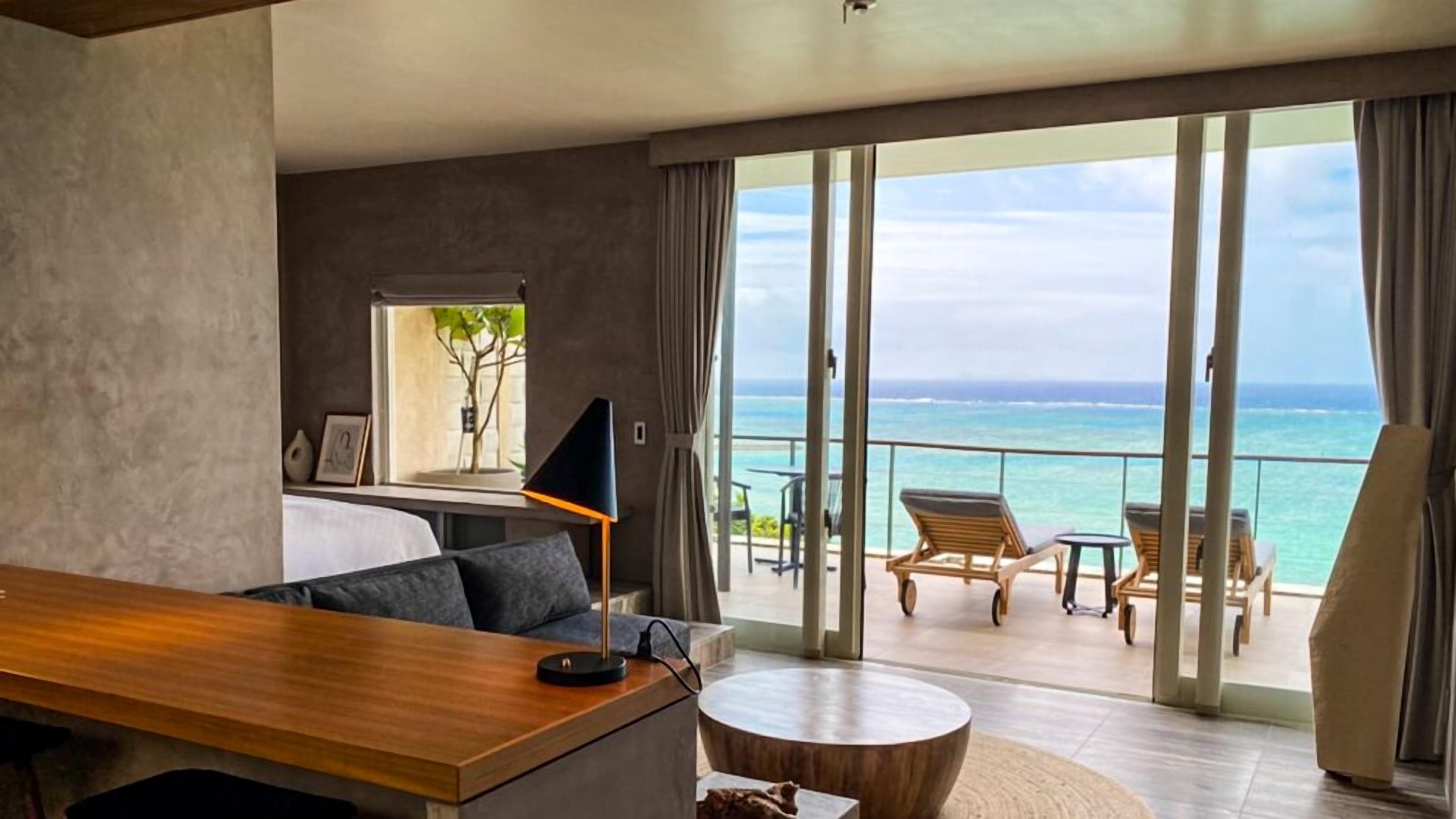 Een moderne hotelkamer met balkon, een ronde houten tafel, een bank en een televisie.