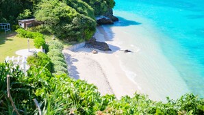 Ein Strand mit klarem türkisblauem Wasser, einem sandigen Ufer und üppiger Vegetation.