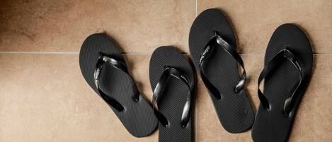Drie paar zwarte slippers op een betegelde vloer.