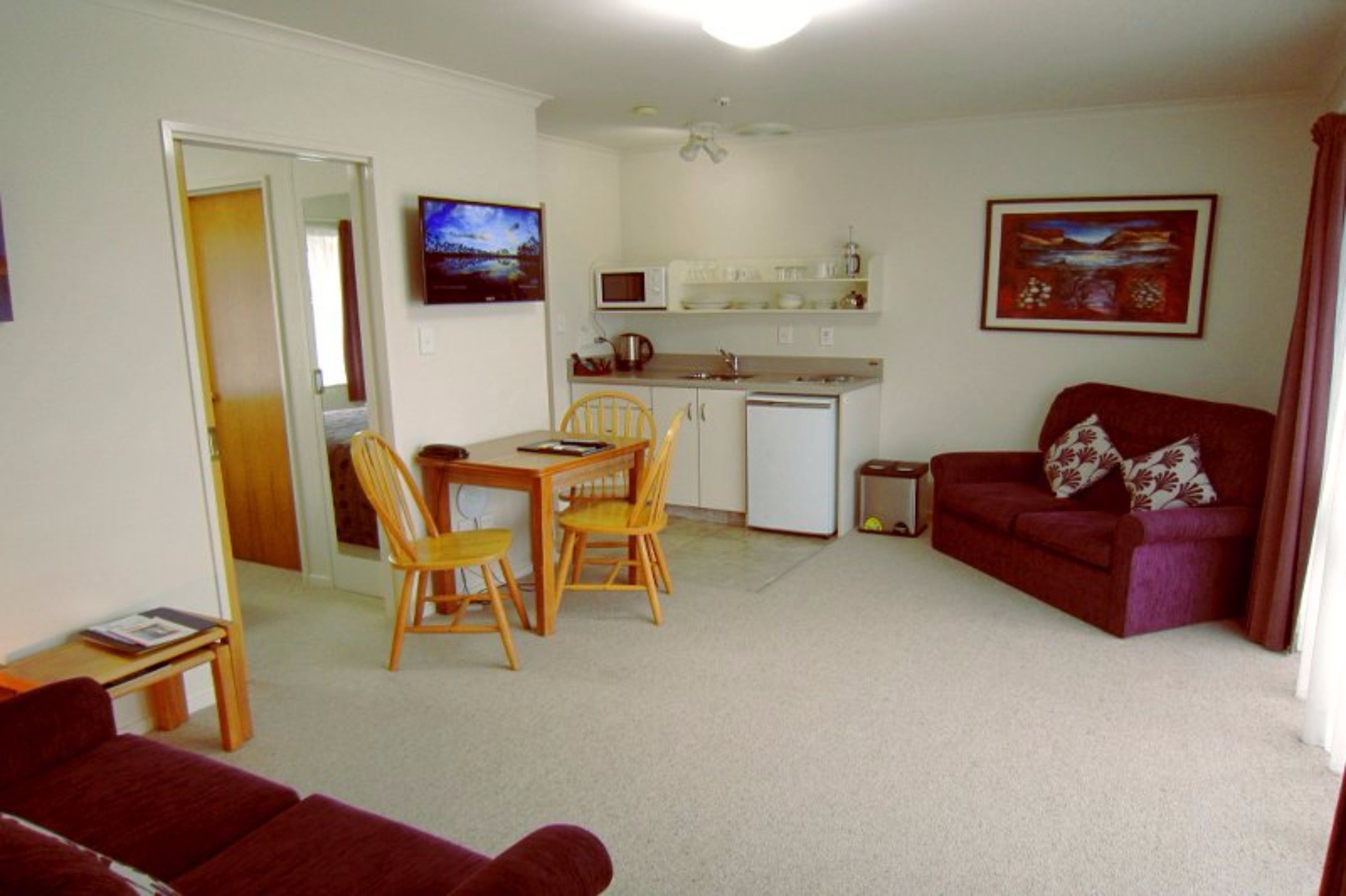 A compact living space with a dining area, kitchenette, and a red sofa.