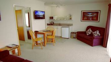 A compact living space with a dining area, kitchenette, and a red sofa.