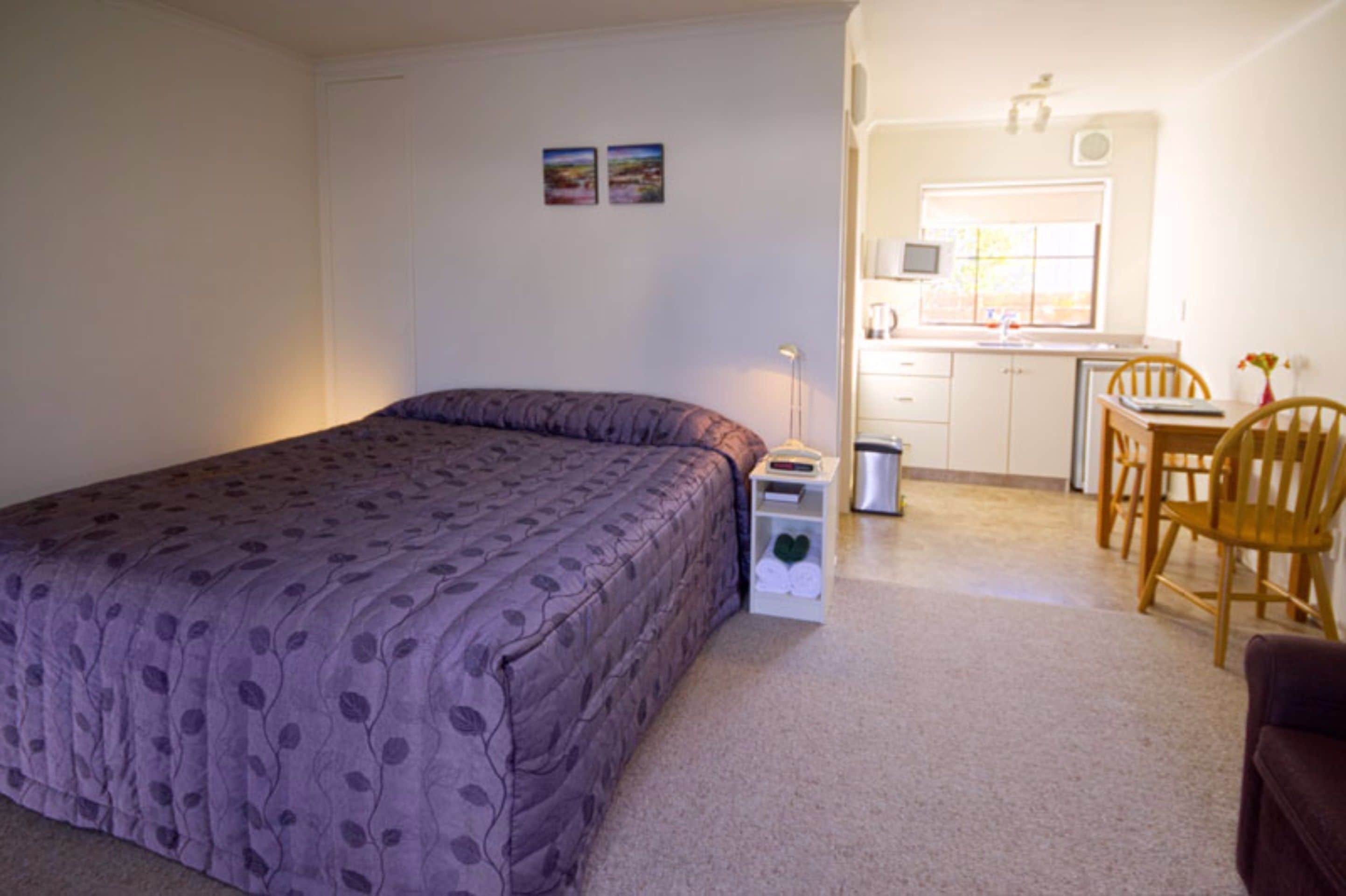 A bedroom with a bed, a desk, and a chair.