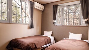A room with two beds, a window with curtains, an air conditioning unit, and a view of trees.