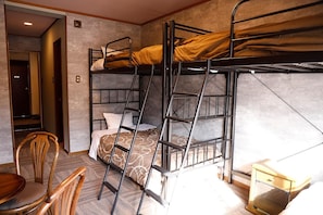 Habitación con literas, una escalera, una silla y una mesita de noche pequeña.