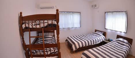 A room with bunk beds, two windows with curtains, an air conditioning unit, and a ceiling fan.