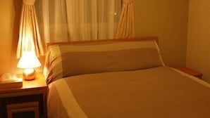Ein Hotelzimmer mit Bett, Nachttisch, Lampe und Vorhängen.
