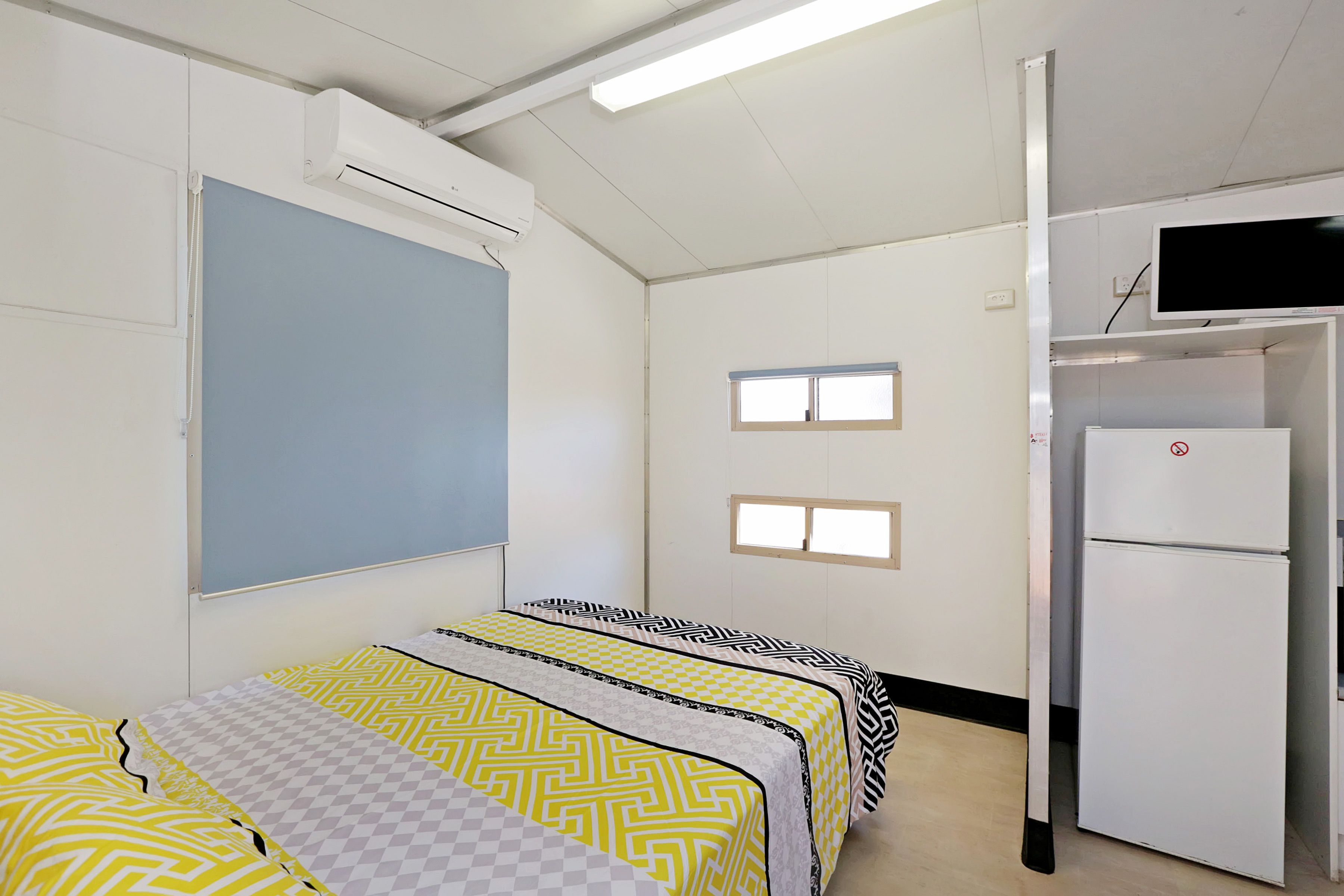 Una habitació amb un llit, una taula, una cadira, una finestra i una porta.