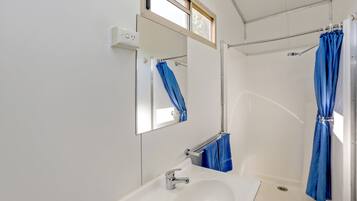 Une salle de bain avec un lavabo blanc, un miroir et une douche avec des rideaux bleus.