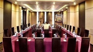 A conference room with long tables and chairs, a stage, and a bar area. - Orchardz Ayani (Pontianak)