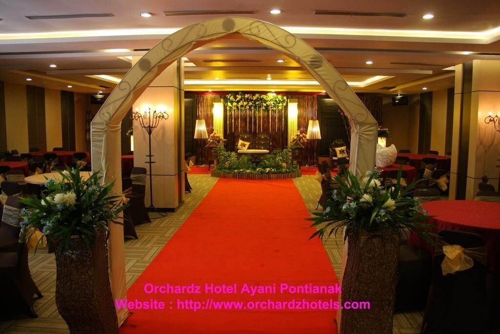 A hotel lobby with a red carpet, a floral arrangement, and a chandelier.