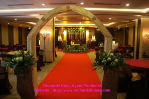 A hotel lobby with a red carpet, a floral arrangement, and a chandelier.