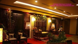 A hotel lobby with traditional decor, including wooden furniture and a red carpet. - Orchardz Ayani (Pontianak)