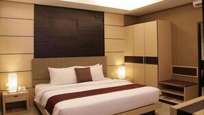 A modern hotel room with a large bed, bedside tables, a wardrobe, and built-in shelving. - Orchardz Ayani (Pontianak)