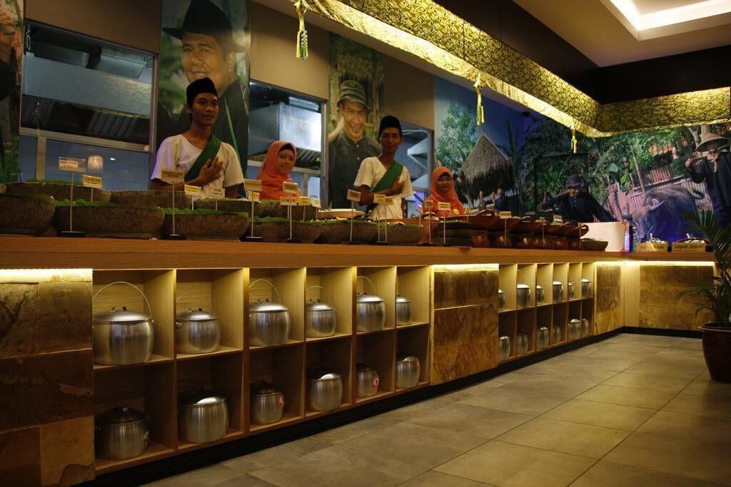 A reception area with a long counter, shelves with metal containers, and a mural depicting traditional figures.