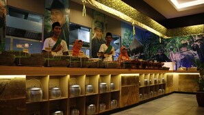 A reception area with a long counter, shelves with metal containers, and a mural depicting traditional figures. - Orchardz Ayani (Pontianak)