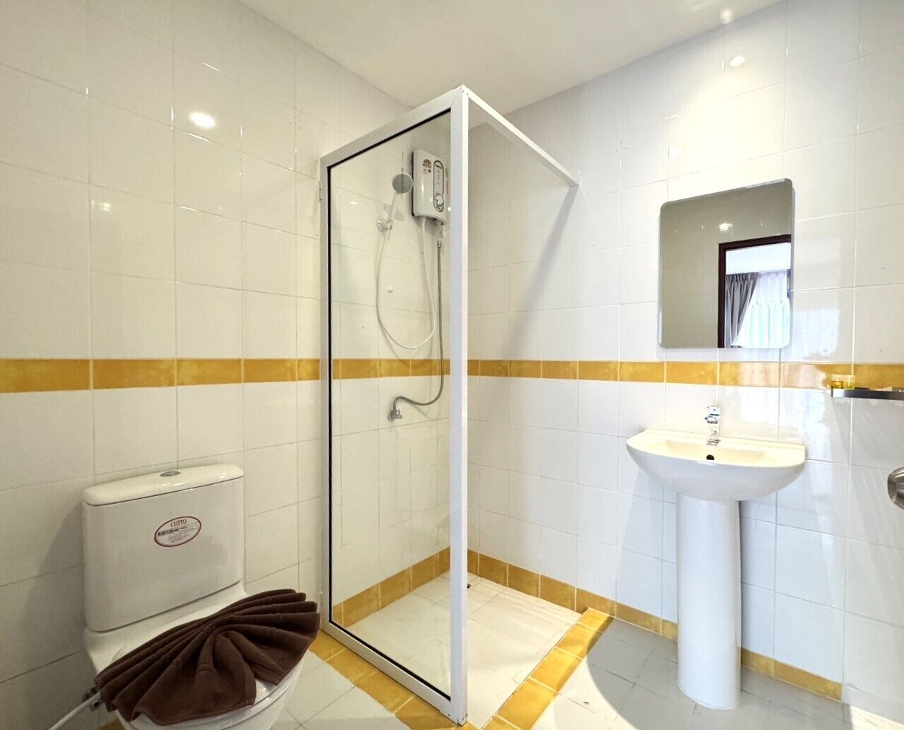 A bathroom with a glass-enclosed shower, a white sink, and a toilet.
