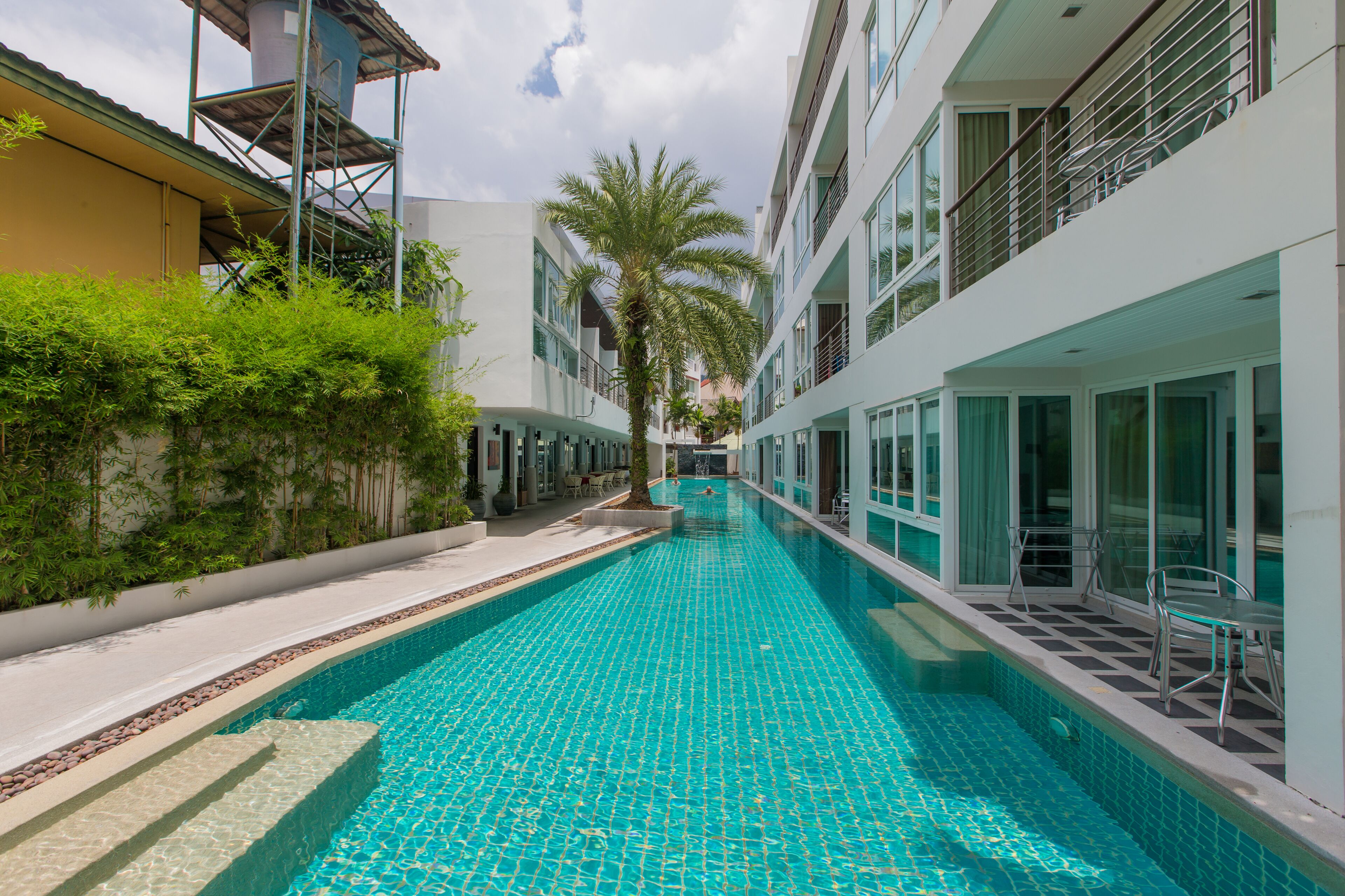 A swimming pool with a tiled floor, surrounded by buildings with balconies and windows.