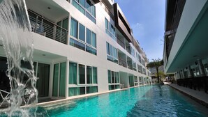 A modern hotel with a swimming pool, large windows, and a waterfall feature. - The Palms Kamala Beach (Kamala)