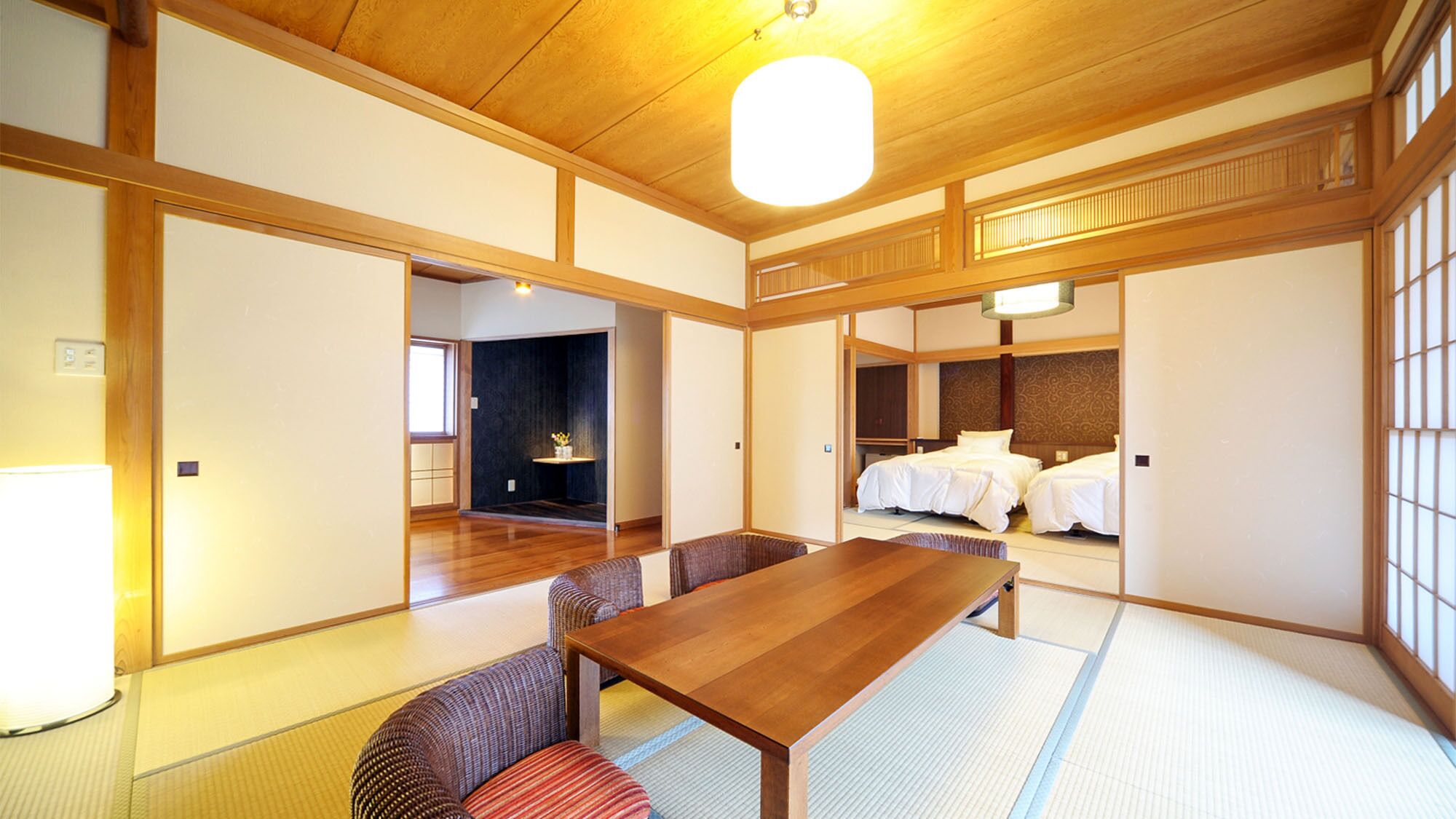 Una habitación japonesa tradicional con suelo de tatami, una mesa de madera para comer y dos esterillas de tatami con almohadillas.