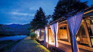 A wooden cabin with a deck, curtains, and a view of mountains. - Takanosu Onsen Takanosukan (Sekikawa)