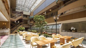 A spacious indoor atrium with multiple levels, seating areas, and a central tree. - Yunokuni Tensyo (Kaga)