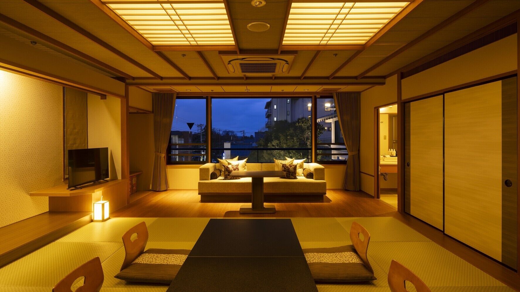 A traditional Japanese room with tatami flooring, a low table, cushions, and sliding doors.