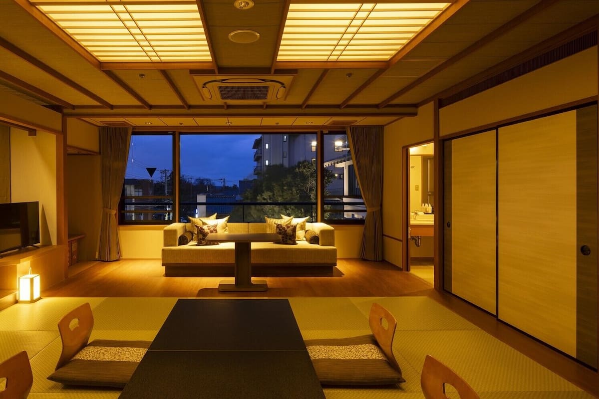 A traditional Japanese room with tatami flooring, a low table, cushions, and sliding doors.