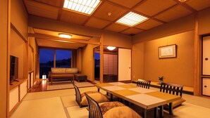 A traditional Japanese-style room with tatami flooring, a low table with cushions, and sliding doors leading to a balcony. - Yunokuni Tensyo (Kaga)