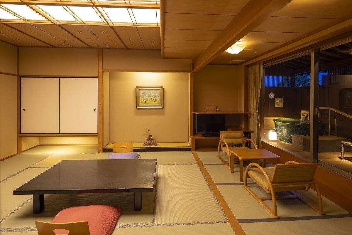 Ein traditioneller japanischer Raum mit Tatami-Bodenbelag, einem niedrigen Tisch, einer Couch und einer Schiebetür.