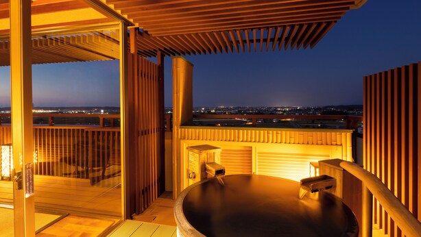 A hot tub on a balcony with a city view at dusk. - Yunokuni Tensyo (Kaga)