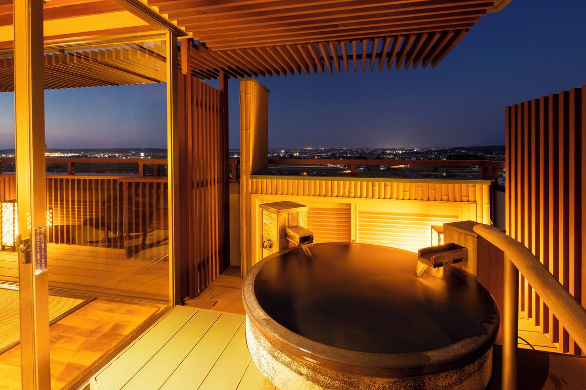 Ein Whirlpool auf einem Balkon mit Blick auf die Stadt im Abendrot.