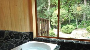 A bathroom with a stone wall, a wooden door, and a window with a view of a garden. - All Resort Service Holiday Homes and Cottages to Rent (Inawashiro)