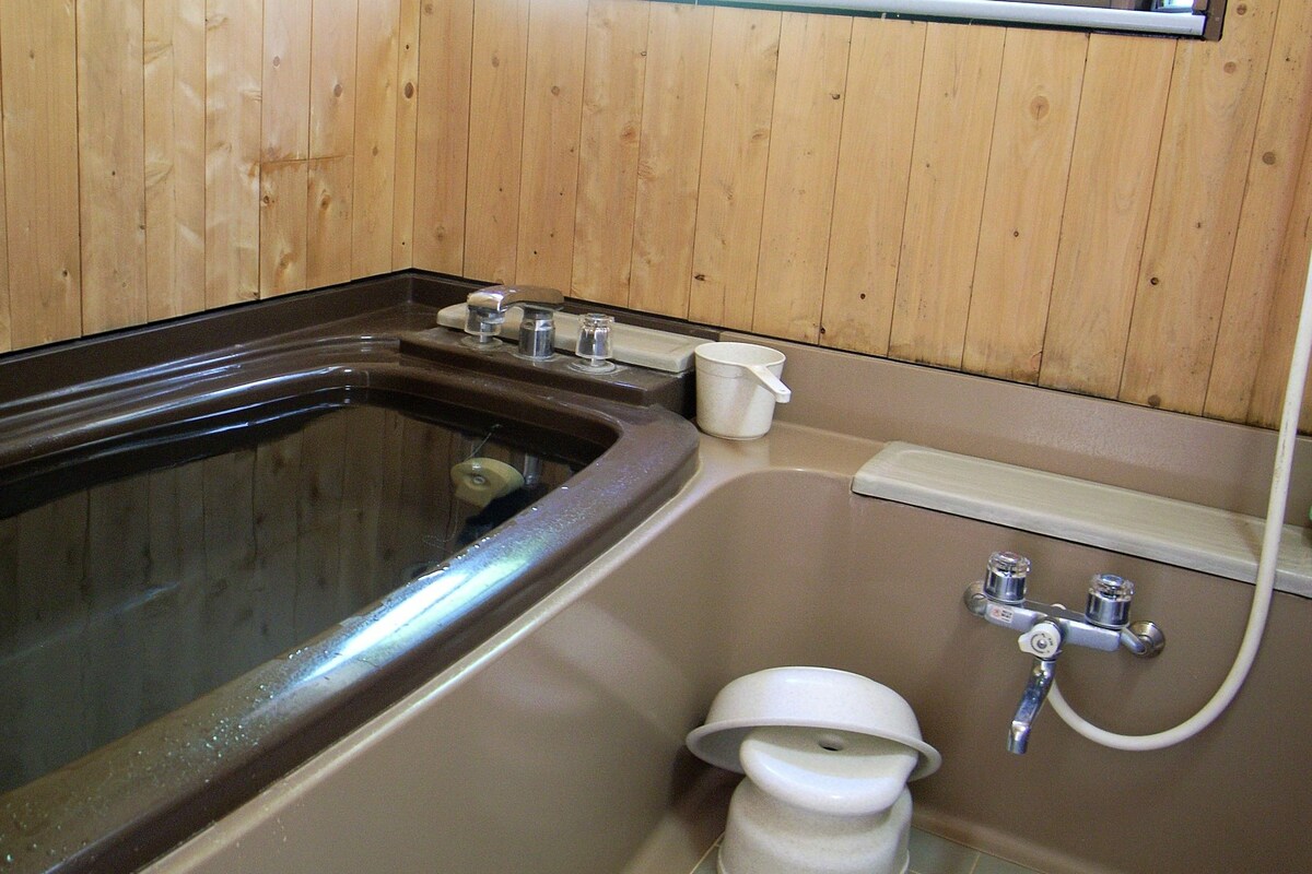 A bathroom with a bathtub, a toilet, and a shower area.