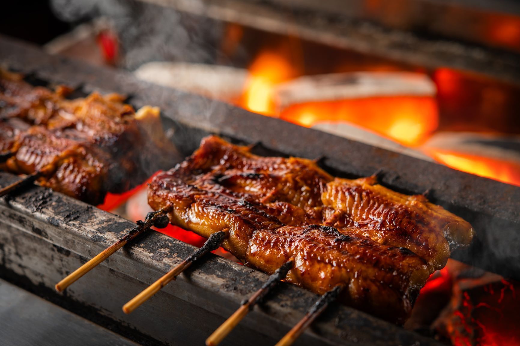 Skewered meats being grilled over an open flame.