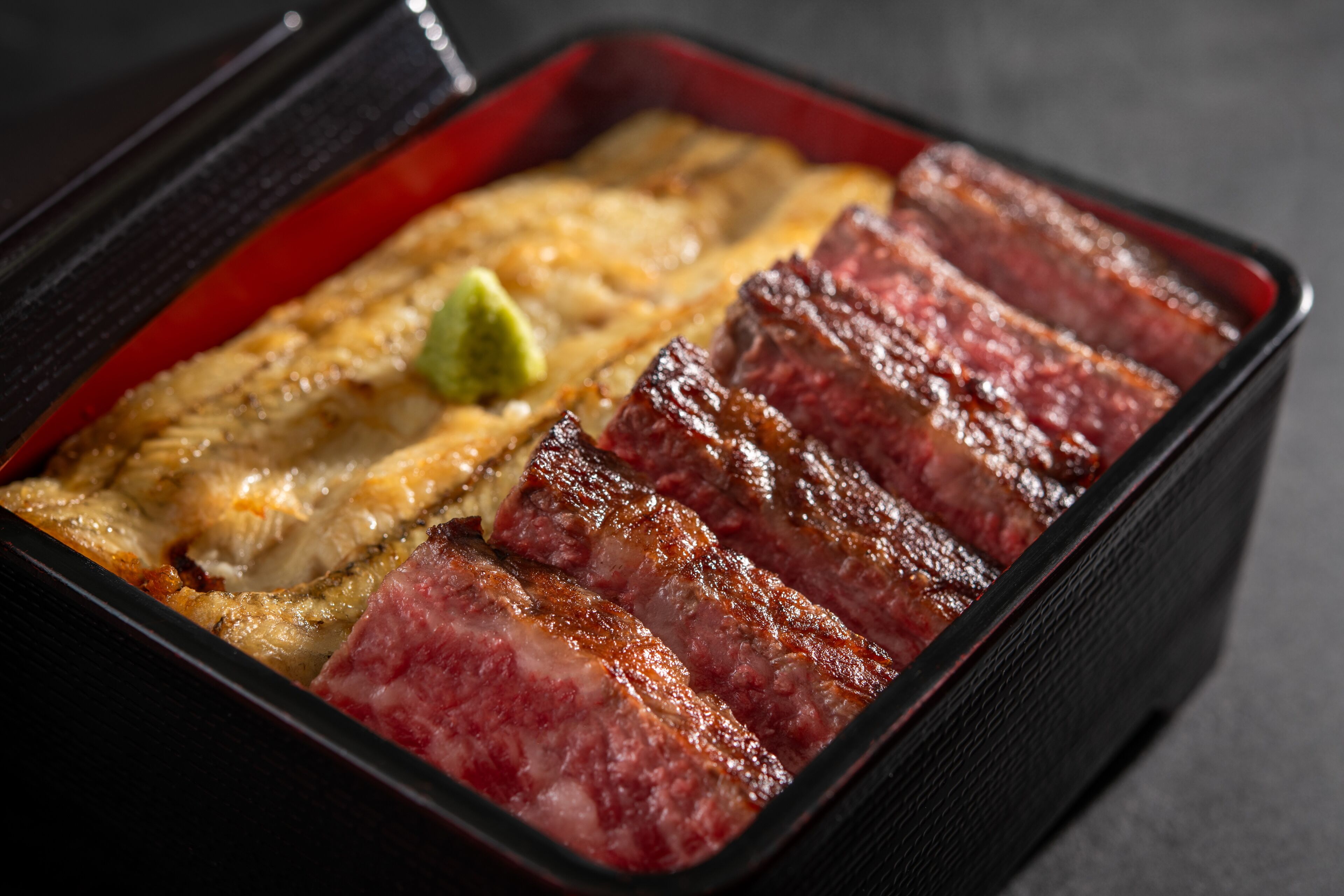A rectangular black tray with slices of grilled meat and a green garnish.