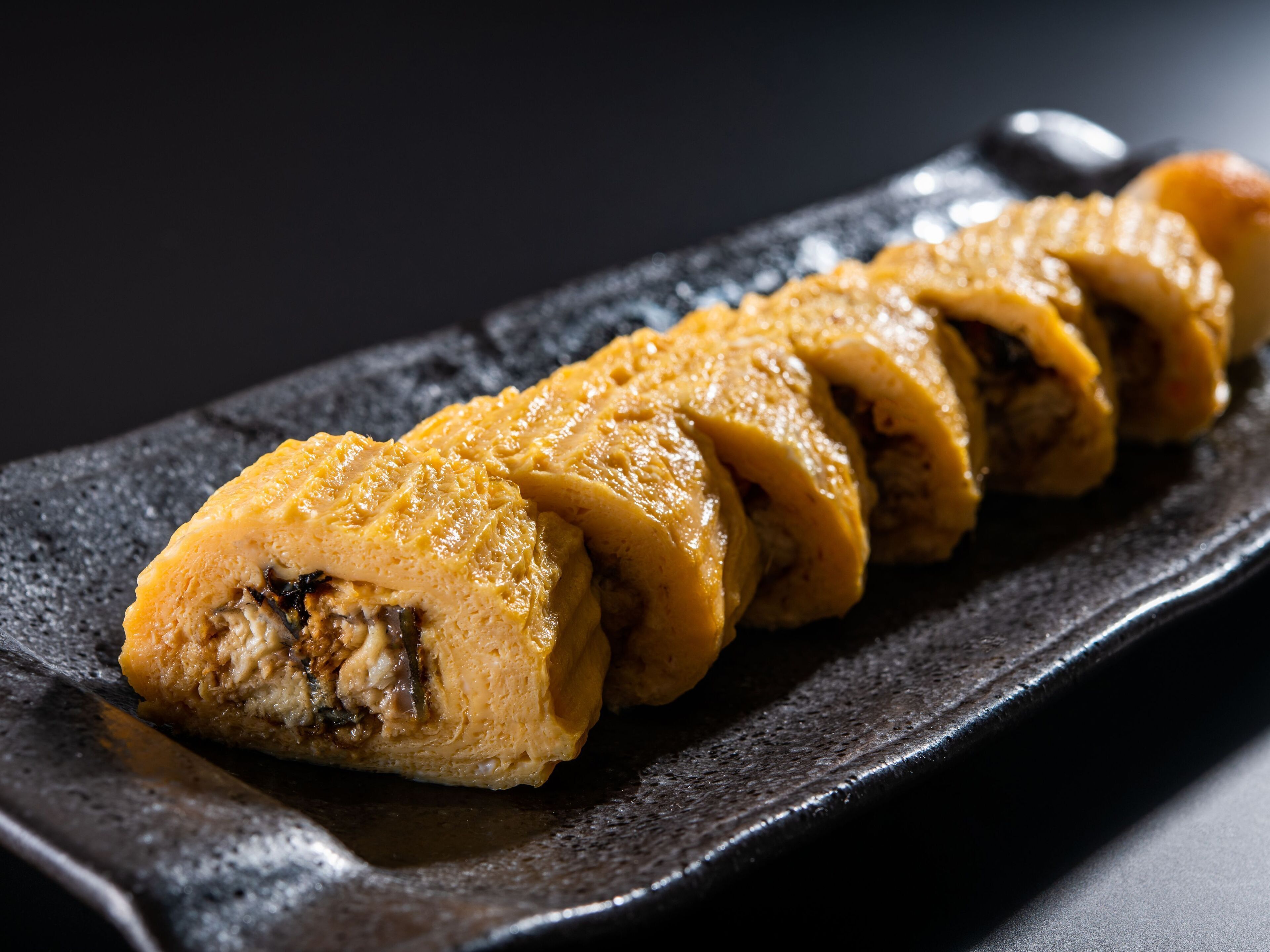 A sushi dish on a dark plate.