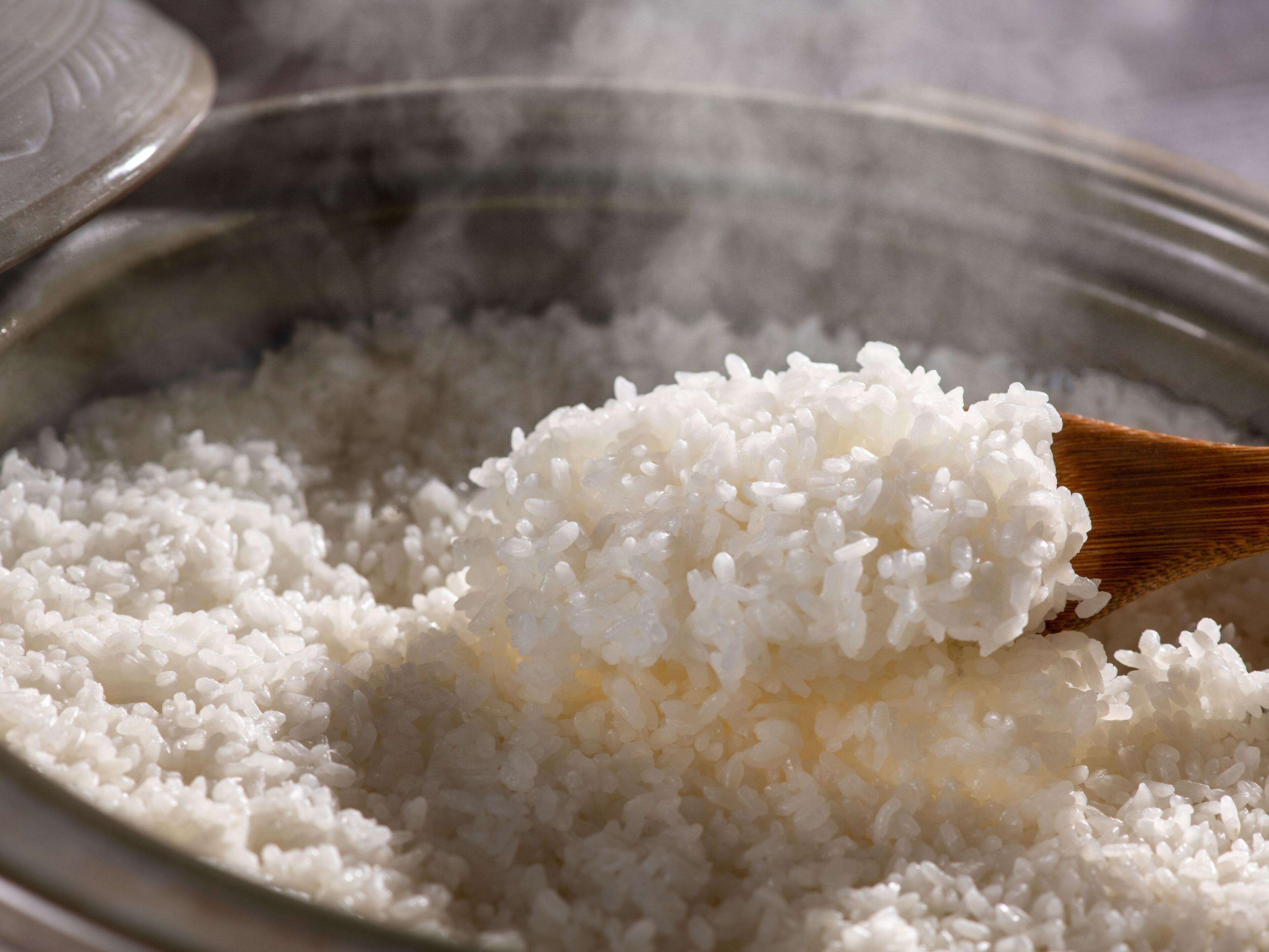 A bowl of white rice with steam rising from it.