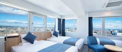 A hotel room with two beds, a chair, a small table, and large windows offering a city view.