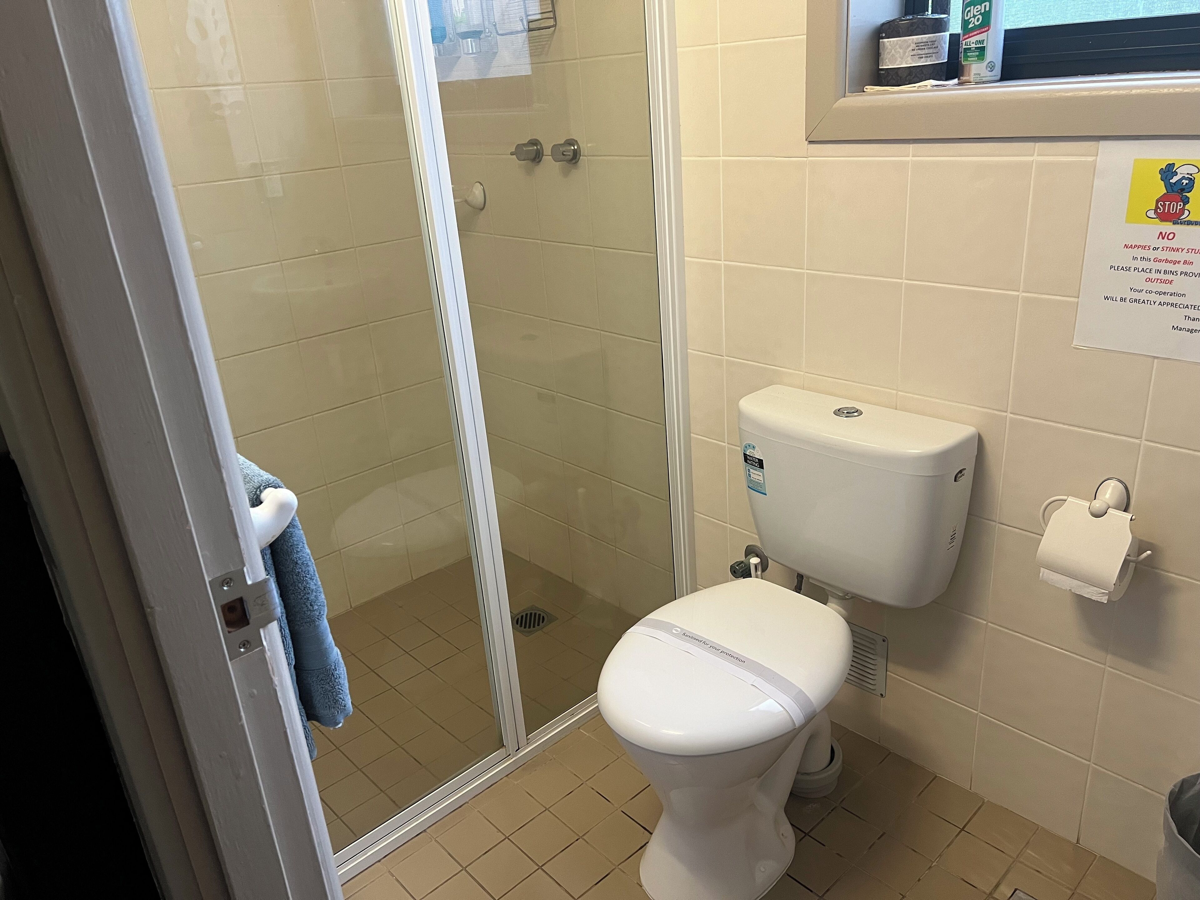 Ein Badezimmer mit Toilette, einer Duschkabine aus Glas und einem Toilettenpapierhalter.