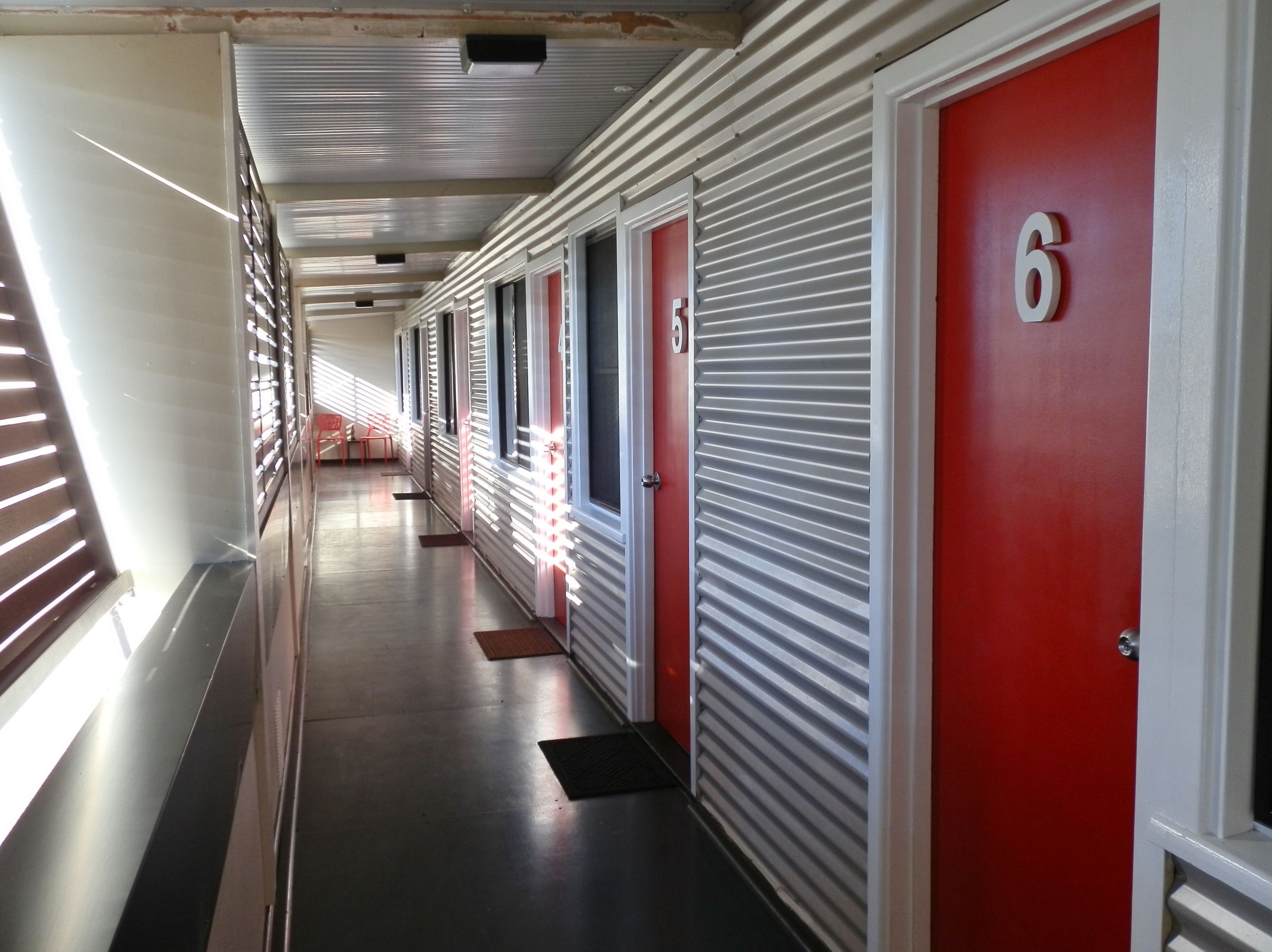 A hotel corridor with red doors, each marked with a number.