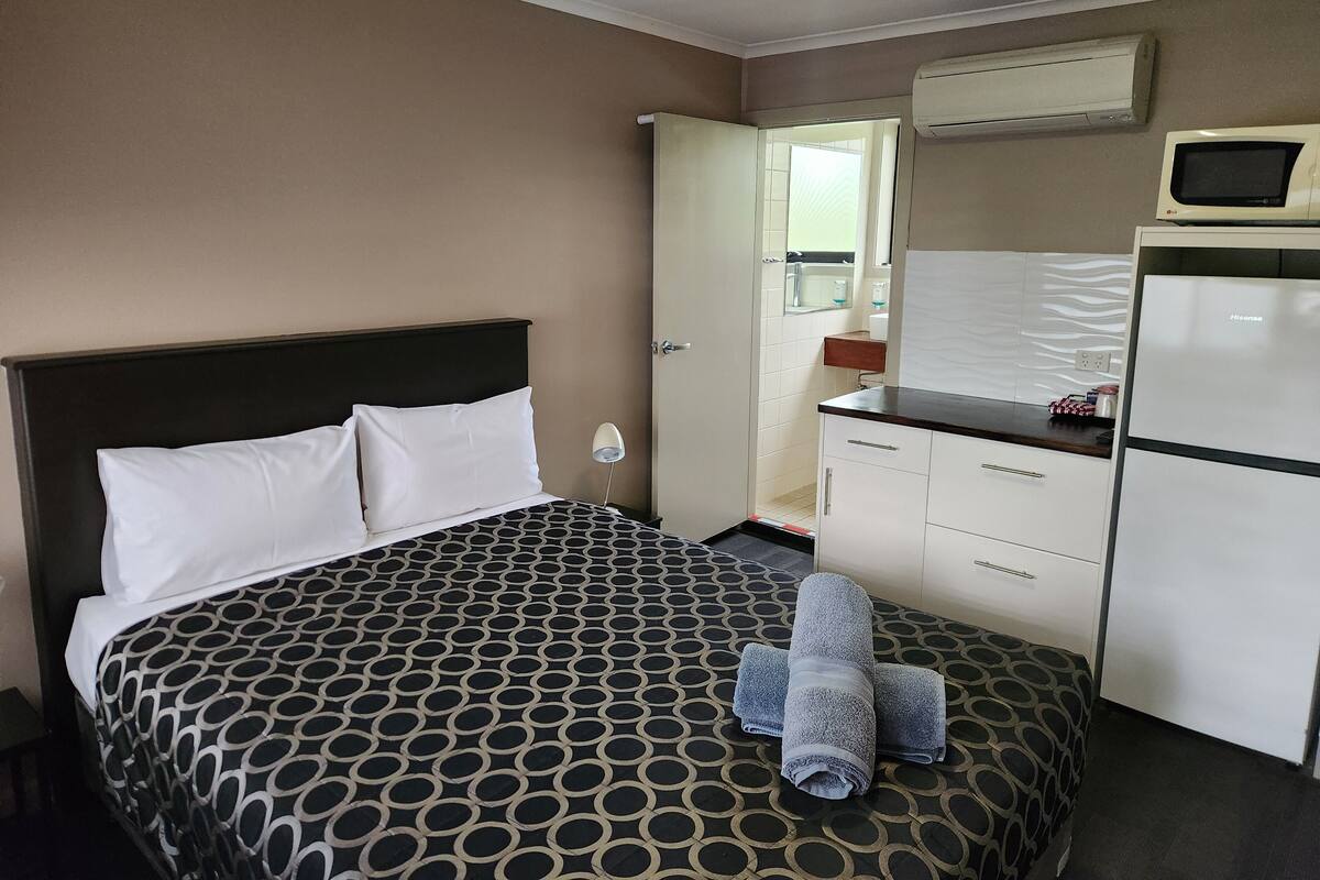 Ein Hotelzimmer mit Bett, Schreibtisch, Kühlschrank und Mikrowelle.