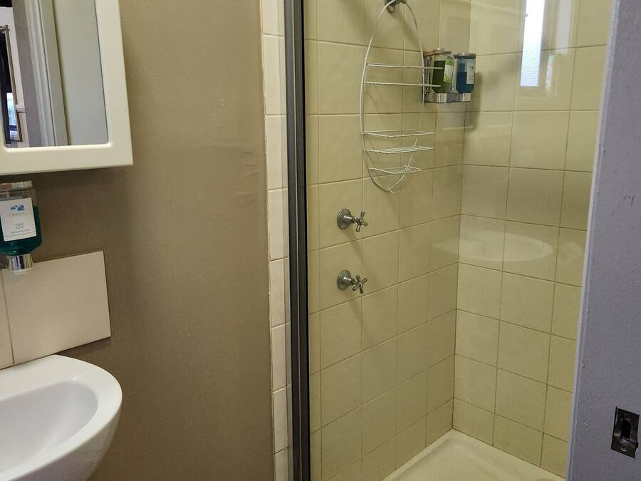 Un baño con cabina de ducha de vidrio, un lavabo blanco y un espejo sobre el lavabo.