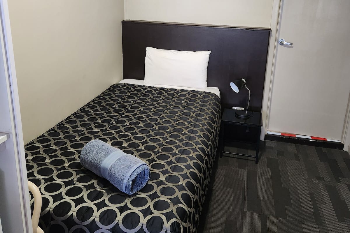 Ein Hotelzimmer mit Bett, Nachttisch, Lampe und Tür.