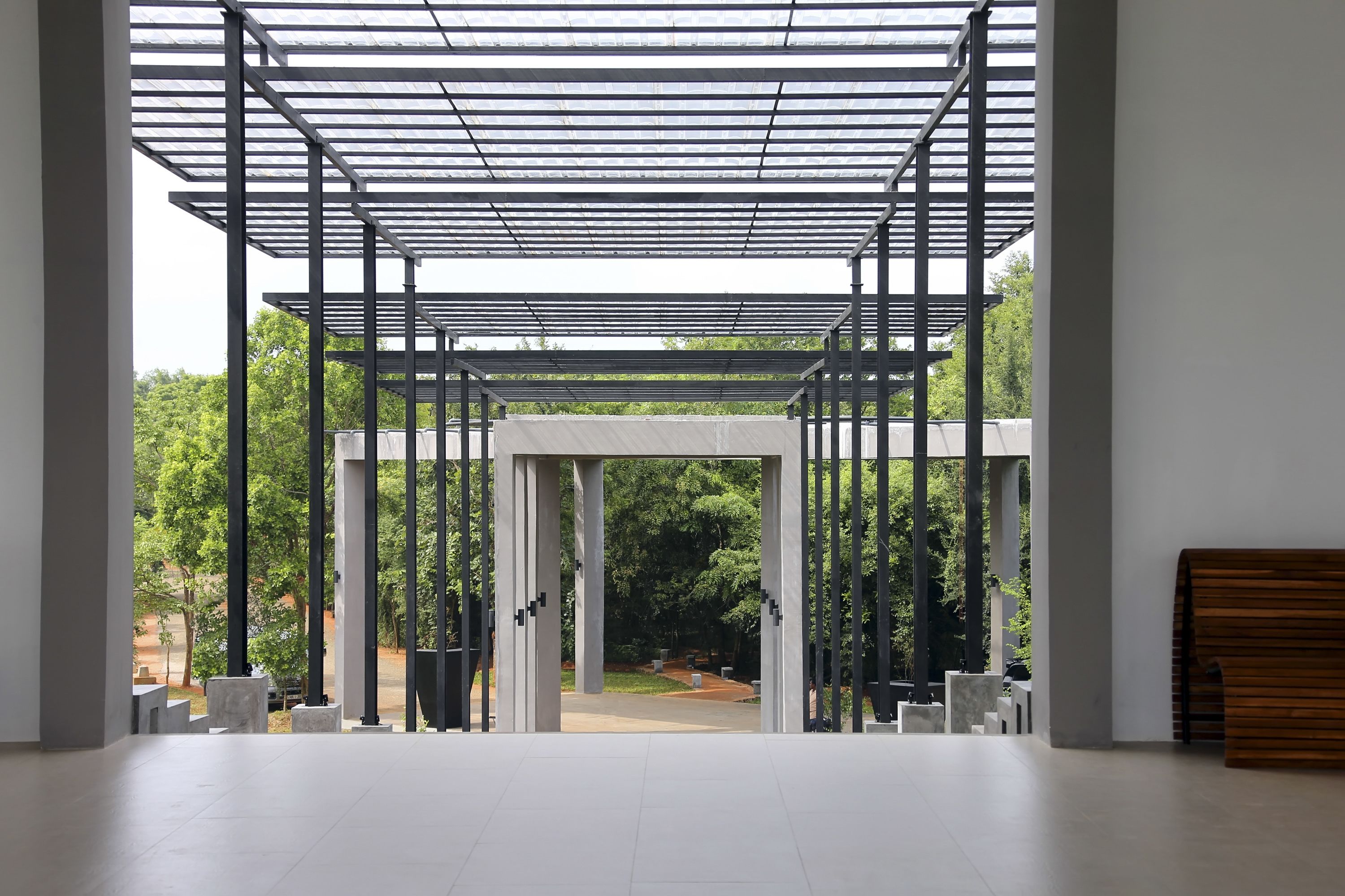 An interior space with a modern architectural design, featuring a glass ceiling and a view of an outdoor garden area.